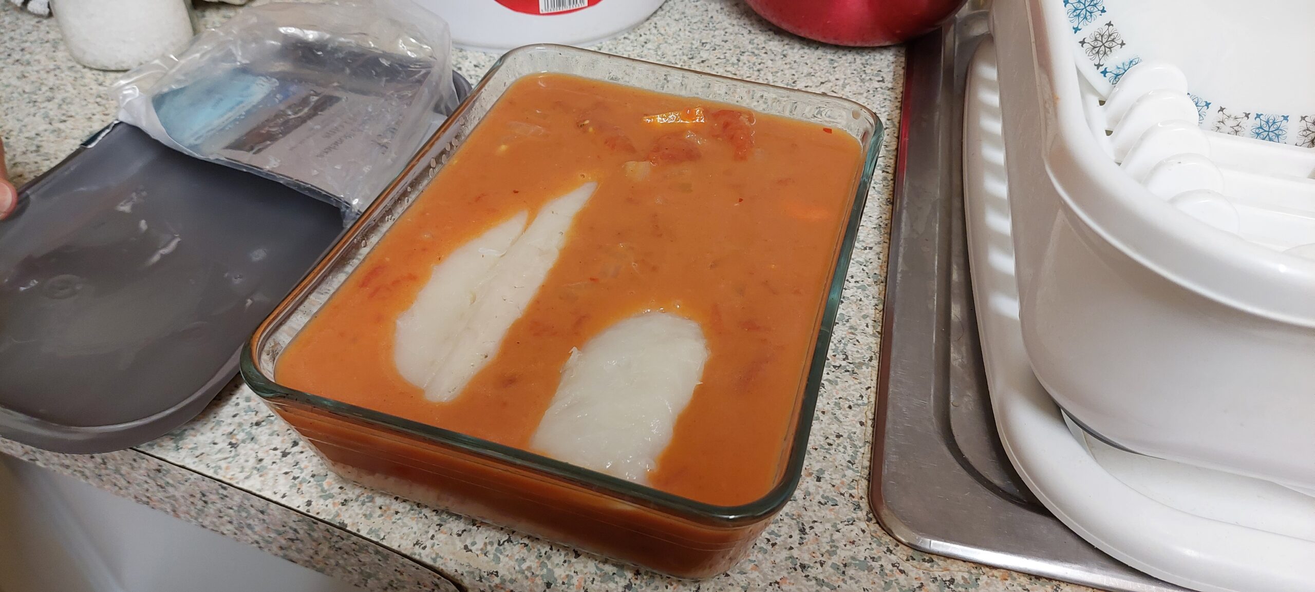 Two cod loins and the sauce in a pyrex dish.